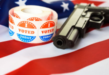 Diffusione delle armi in America, il sondaggio Nbc Diffusione delle armi in America, il sondaggio Nbc: pistola con bandiera americana e adesivo "i vote"
