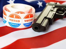 Diffusione delle armi in America, il sondaggio Nbc Diffusione delle armi in America, il sondaggio Nbc: pistola con bandiera americana e adesivo "i vote"