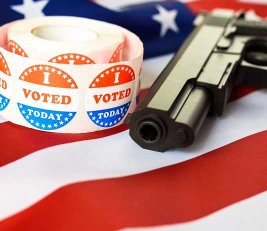 Diffusione delle armi in America, il sondaggio Nbc Diffusione delle armi in America, il sondaggio Nbc: pistola con bandiera americana e adesivo "i vote"
