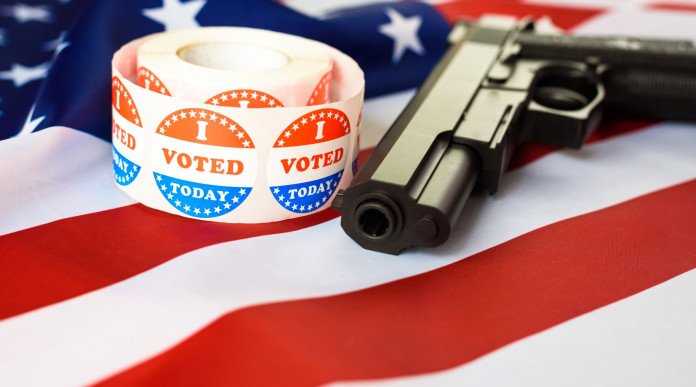 Diffusione delle armi in America, il sondaggio Nbc: pistola con bandiera americana e adesivo 