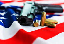 Mercato delle armi in America, la situazione a inizio dicembre Mercato delle armi in America, la situazione a inizio dicembre: pistola con proiettili su bandiera americana