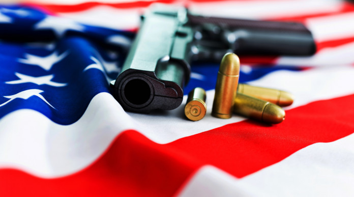 Mercato delle armi in America, la situazione a inizio dicembre: pistola con proiettili su bandiera americana