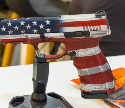 Mercato delle armi in America: i dati finali del 2023 Mercato delle armi in America, i dati finali del 2023: pistola con bandiera americana esposta a fiera delle armi