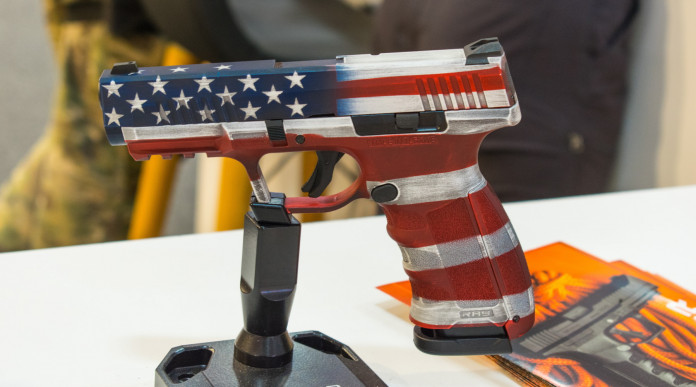 Mercato delle armi in America, i dati finali del 2023: pistola con bandiera americana esposta a fiera delle armi
