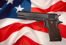 Quanti background check in America nel 2023? Quanti background check in America nel 2023? pistola semiautomatica su bandiera americana