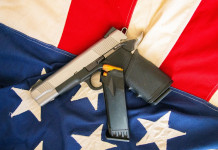 Come sta andando il mercato delle armi in America? Come sta andando il mercato delle armi in America? pistola su bandiera americana, con caricatore di scorta