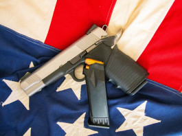 Come sta andando il mercato delle armi in America? Come sta andando il mercato delle armi in America? pistola su bandiera americana, con caricatore di scorta