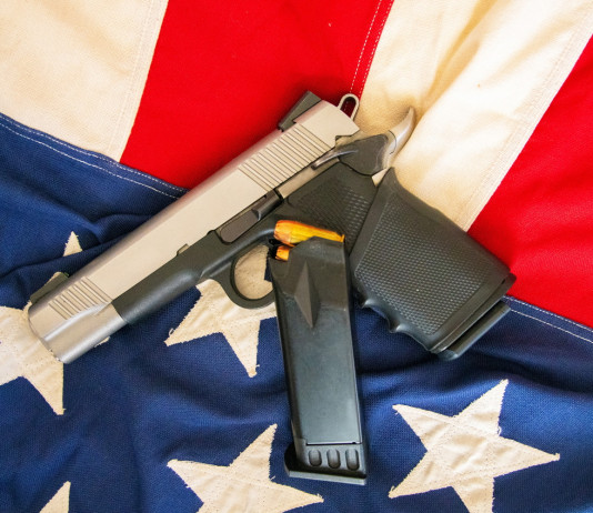 Come sta andando il mercato delle armi in America? Come sta andando il mercato delle armi in America? pistola su bandiera americana, con caricatore di scorta