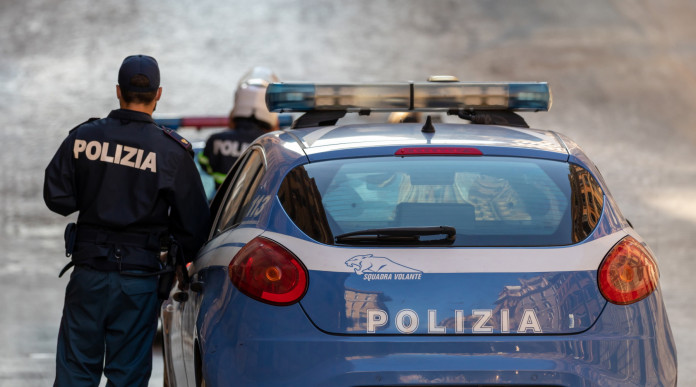 Approvata legge su armi ad agenti senza licenza: poliziotto accanto ad autovettura