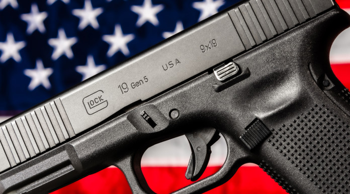 Quanti background check richiesti in America nel 2025 - pistola glock g19 gen 5 davanti a bandiera americana, stelle e strisce